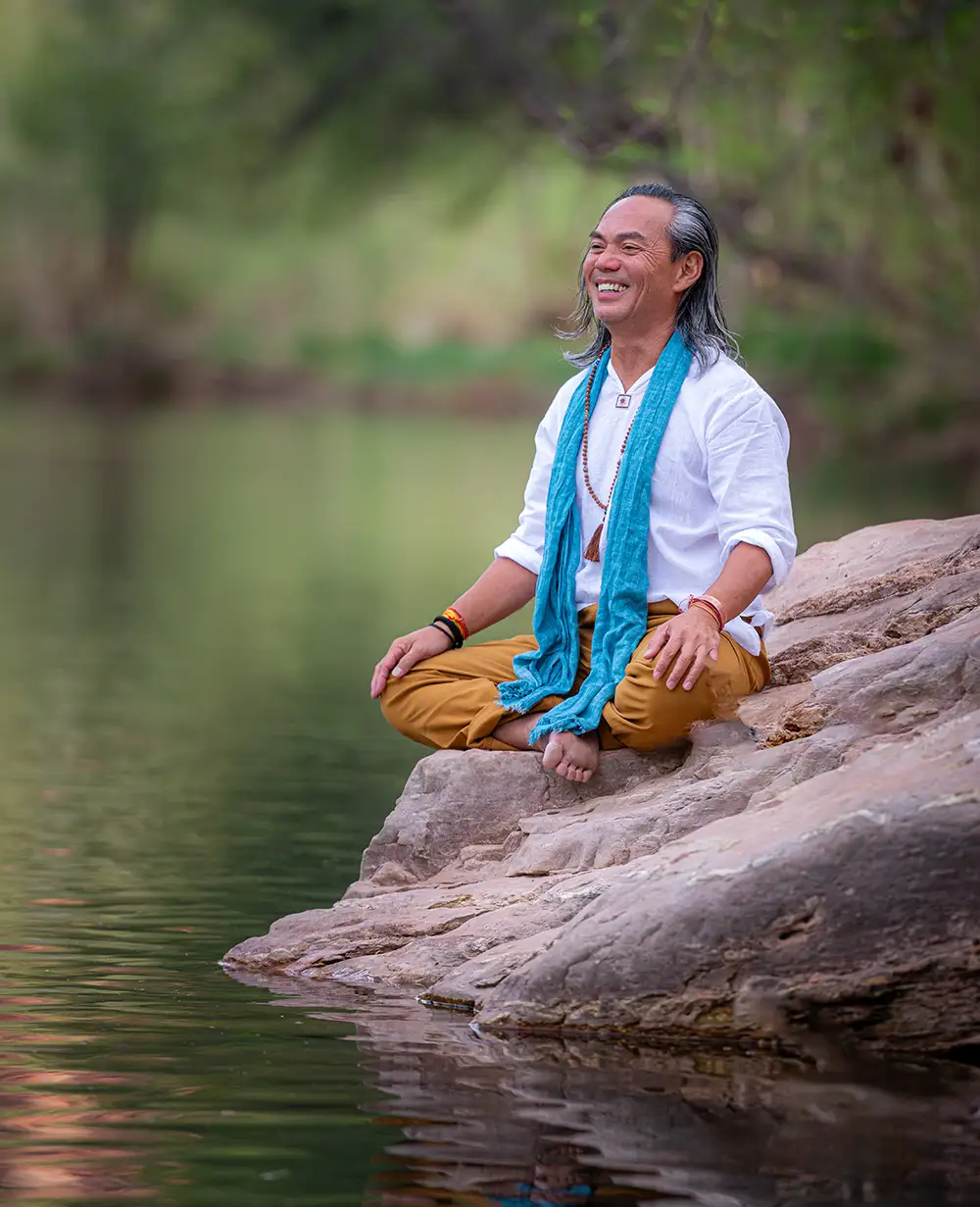 a man sitting on a rock smiling.
